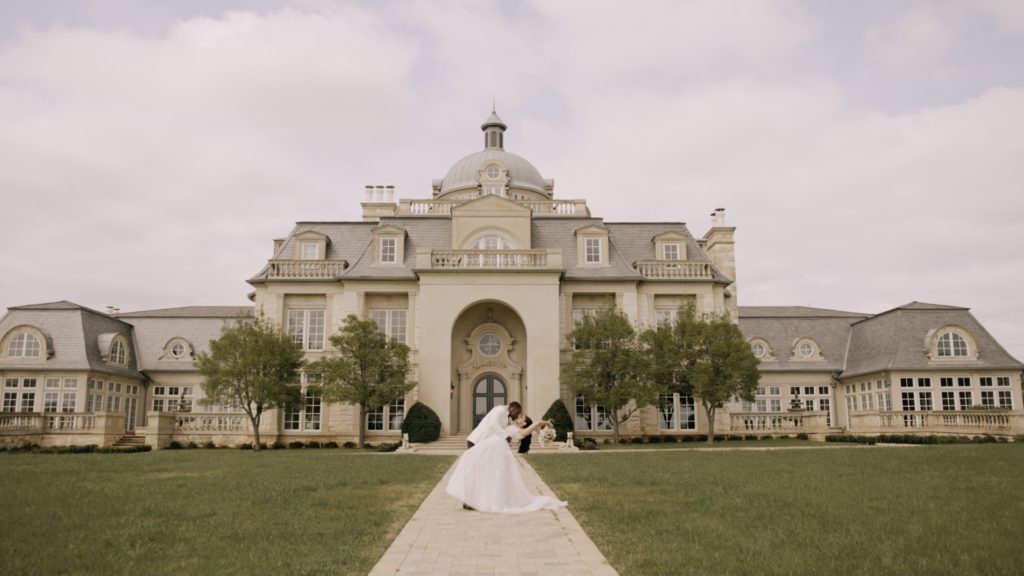bride and groom kissing in front of mansion