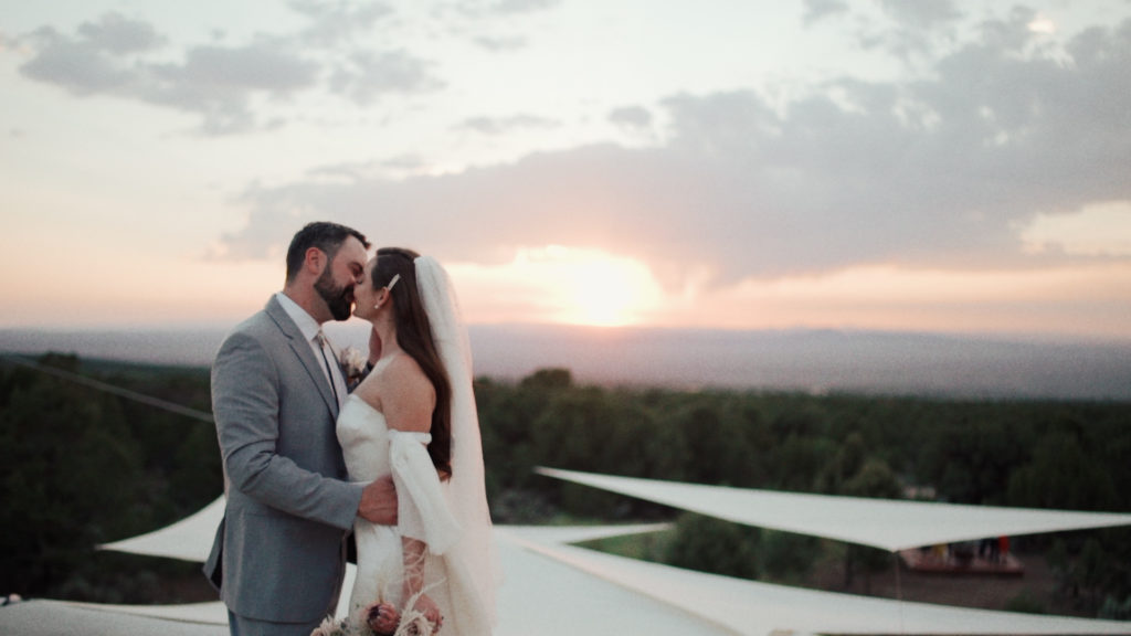 bride and groom embracing with sunset background