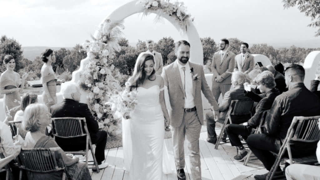 black and white image of a bride and groom walking down the aisle of a wedding ceremony