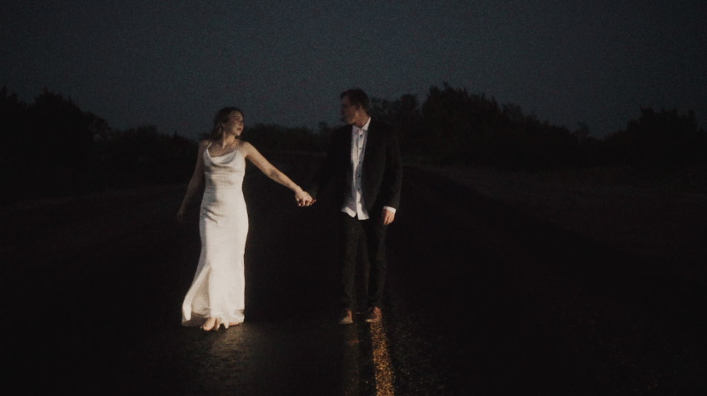 bride and groom walking on a desert road at night