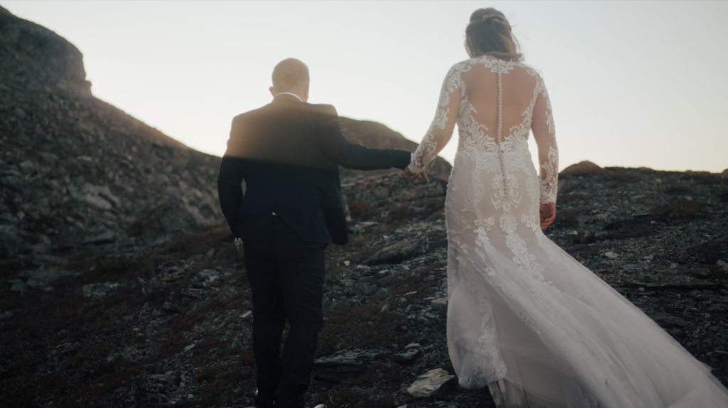 bride and groom holding hands walking on a cliff wedding dress 