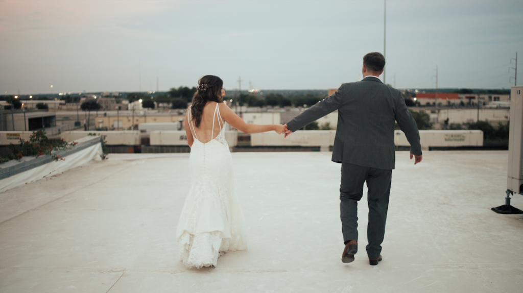 bride and groom holding hands on a rooftop