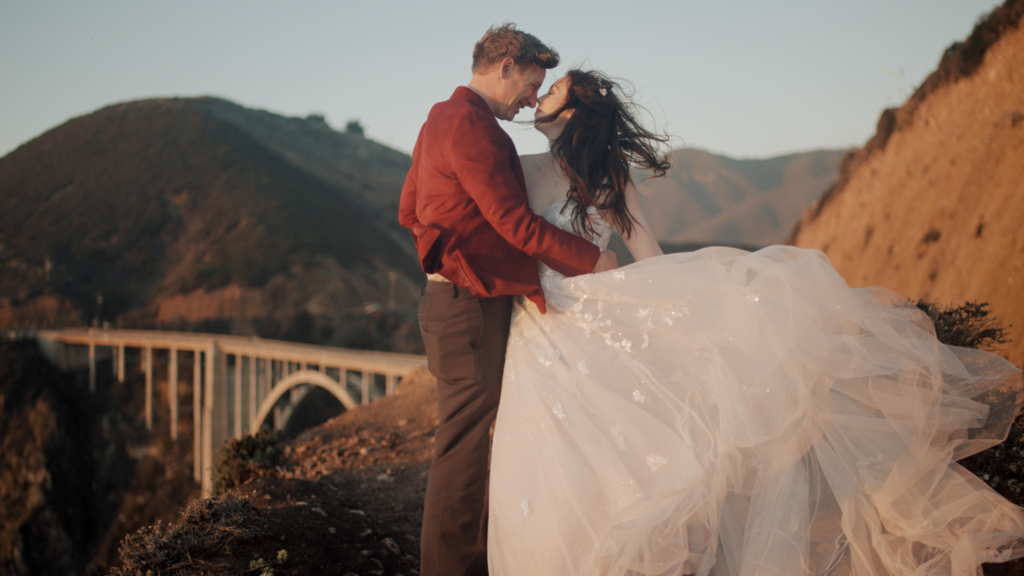 bride and groom standing on scenic overlook at Bixby Bridge