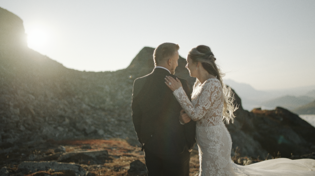 couple embracing on a mountainside cliff at golden hour