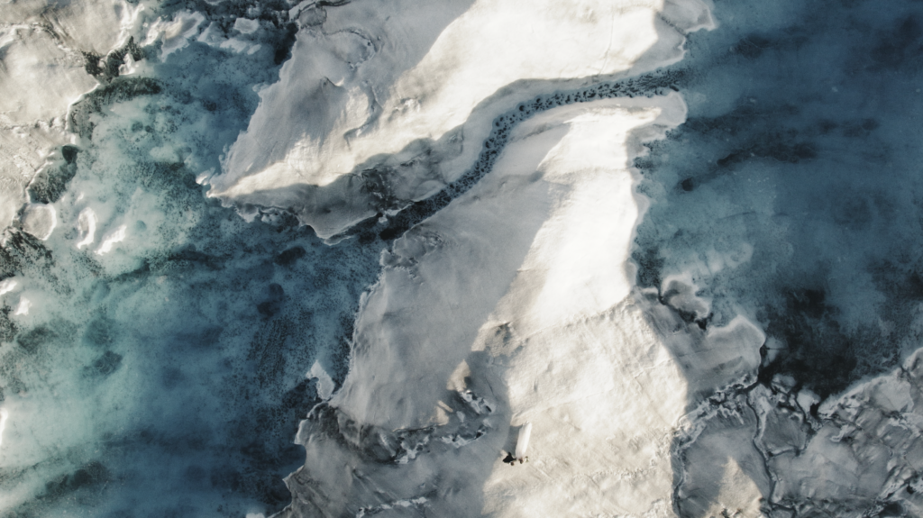 aerial photo of a bride and groom walking on a glacier