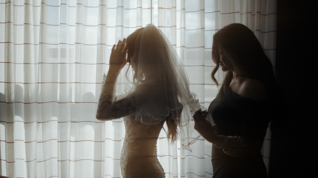 bride putting her veil on with help from her mom
